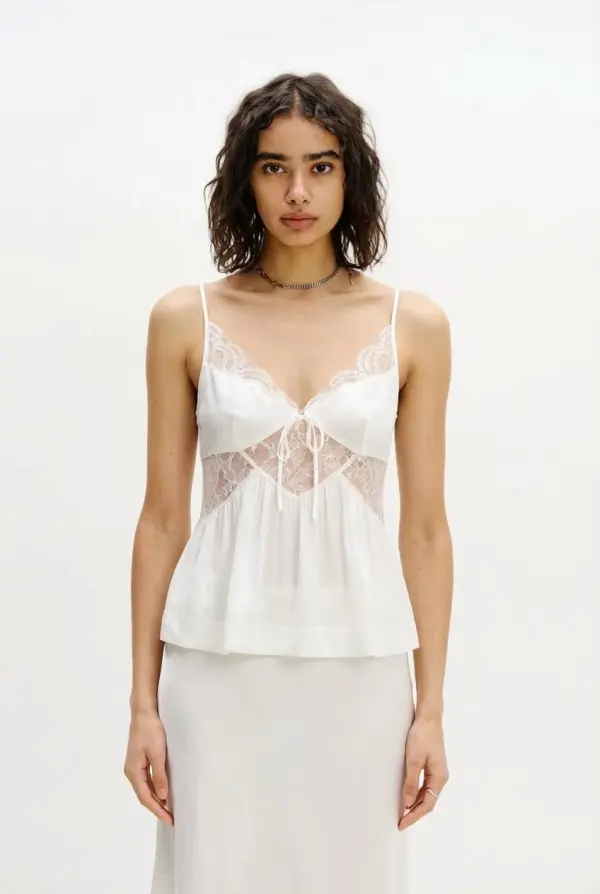 A Woman Is Wearing A Delicate White Lace Top And Skirt In A Minimalist Studio Setting