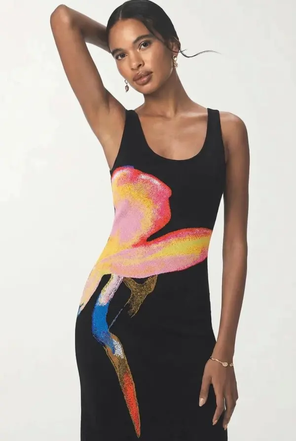 A Woman Poses Gracefully In A Vibrant Artistic Black Dress Against A Neutral Studio Backdrop